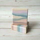 Two soap bars with a pastel color pattern on a wooden surface