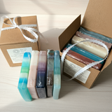 Set of colorful soap bars in a cardboard box on a wooden surface